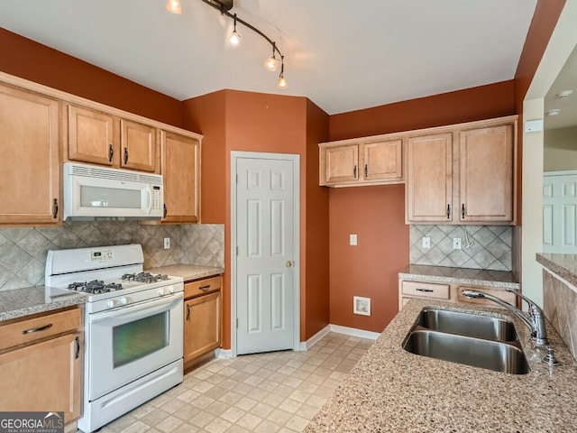 kitchen with tasteful backsplash, light stone countertops, sink, and white appliances