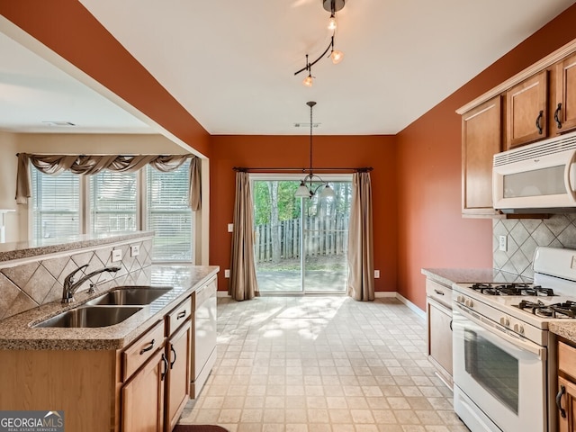 kitchen featuring backsplash, sink, decorative light fixtures, and white appliances