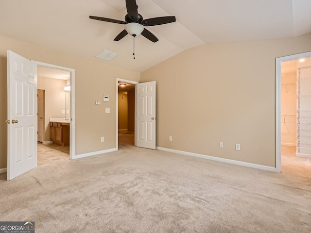 unfurnished bedroom featuring ensuite bathroom, ceiling fan, light colored carpet, and lofted ceiling