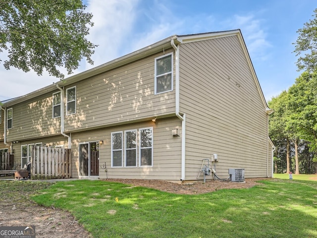 rear view of property featuring a yard and central air condition unit