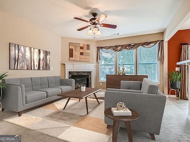 living room featuring a fireplace, light carpet, and ceiling fan