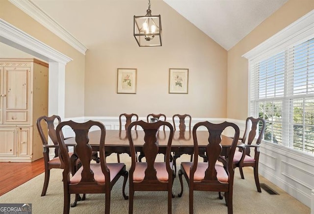 dining space with a chandelier, ornamental molding, light wood-type flooring, and lofted ceiling