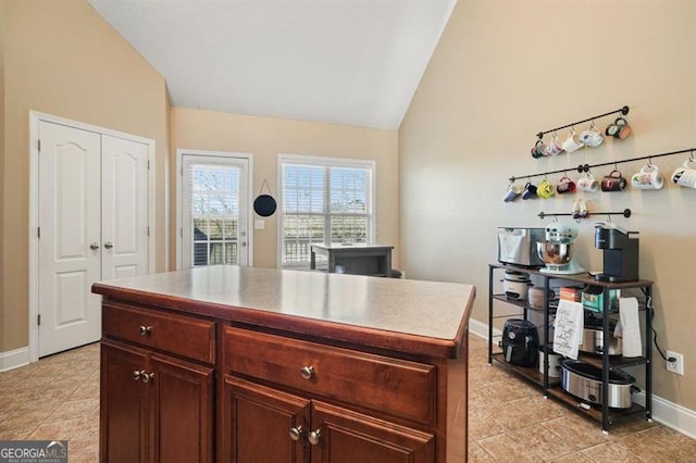 kitchen featuring a center island, light tile patterned flooring, and vaulted ceiling