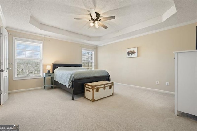 bedroom with light carpet, a textured ceiling, a tray ceiling, ceiling fan, and crown molding