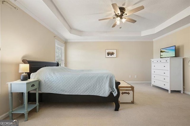 carpeted bedroom with a tray ceiling, ceiling fan, and crown molding