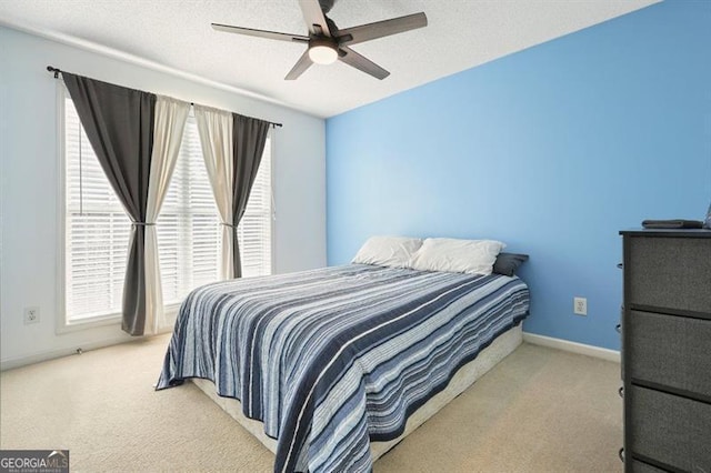 bedroom featuring ceiling fan, light colored carpet, and a textured ceiling