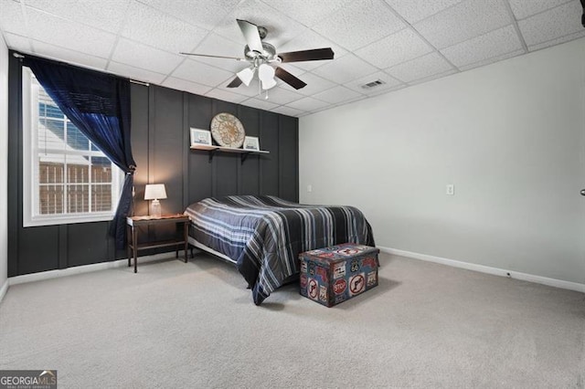 carpeted bedroom with a paneled ceiling and ceiling fan