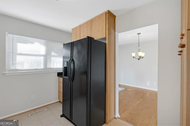 kitchen with a notable chandelier, light brown cabinets, black fridge with ice dispenser, and hanging light fixtures