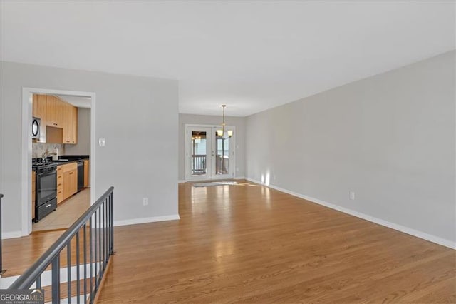 unfurnished living room featuring light hardwood / wood-style flooring and a notable chandelier