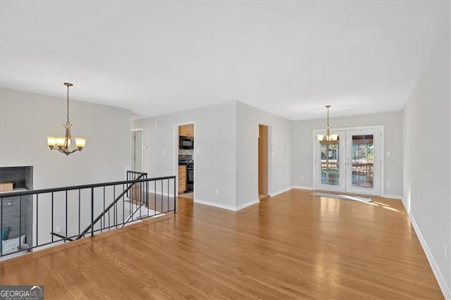 spare room with hardwood / wood-style flooring, a fireplace, and an inviting chandelier