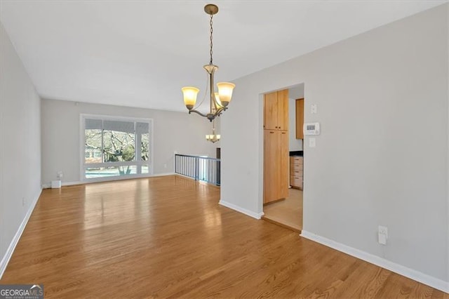 unfurnished dining area featuring hardwood / wood-style flooring and an inviting chandelier