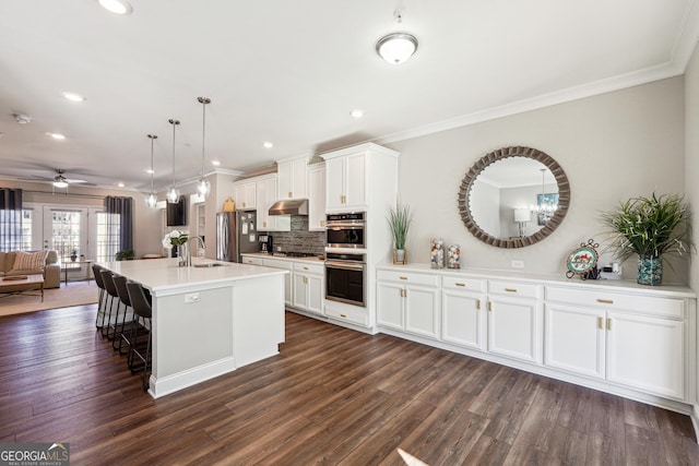 kitchen featuring hanging light fixtures, sink, white cabinetry, a center island with sink, and stainless steel appliances