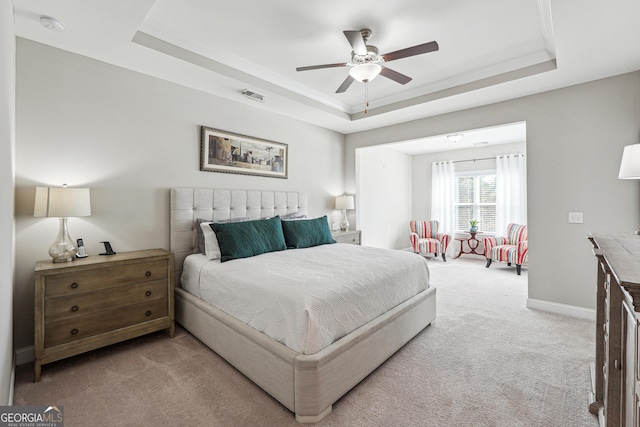 carpeted bedroom featuring ceiling fan and a tray ceiling