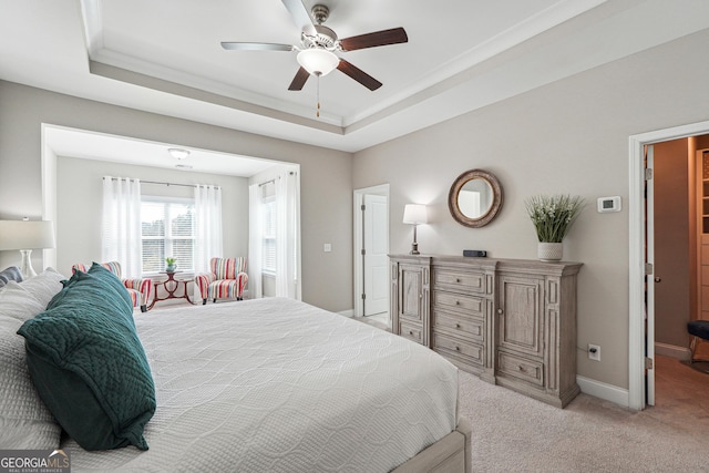 carpeted bedroom with crown molding, ceiling fan, and a raised ceiling