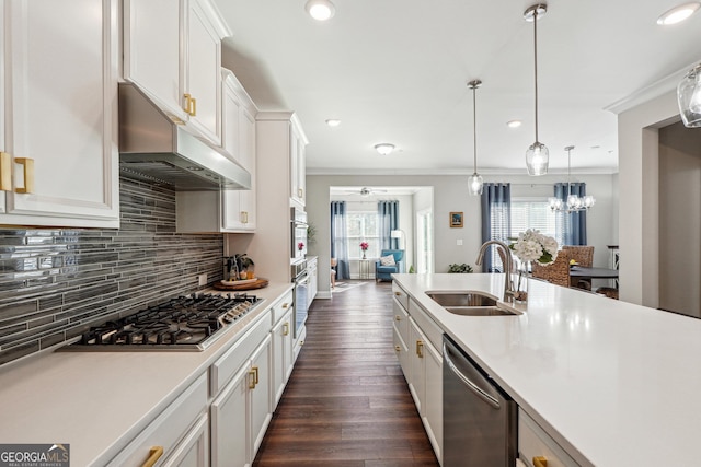 kitchen with decorative light fixtures, white cabinetry, stainless steel appliances, sink, and ornamental molding