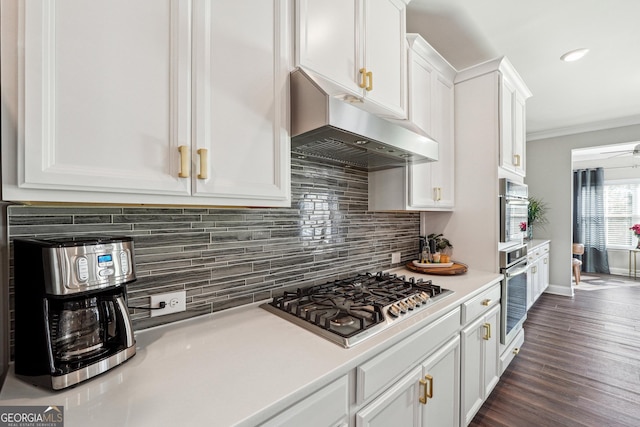 kitchen with ceiling fan, extractor fan, white cabinetry, ornamental molding, and stainless steel gas cooktop