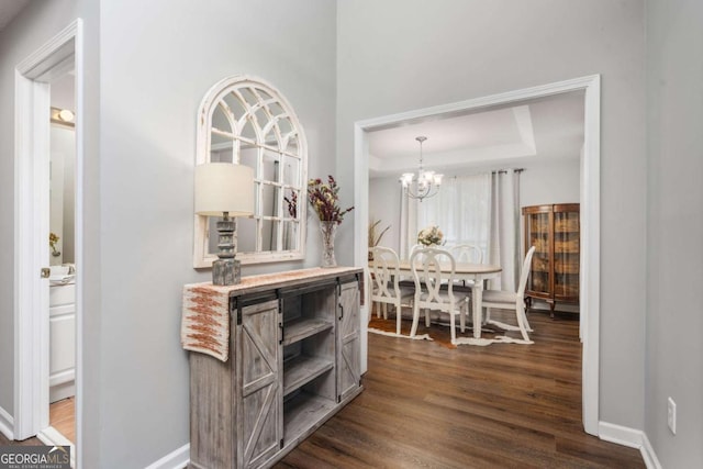 interior space featuring a tray ceiling, dark hardwood / wood-style flooring, and a chandelier