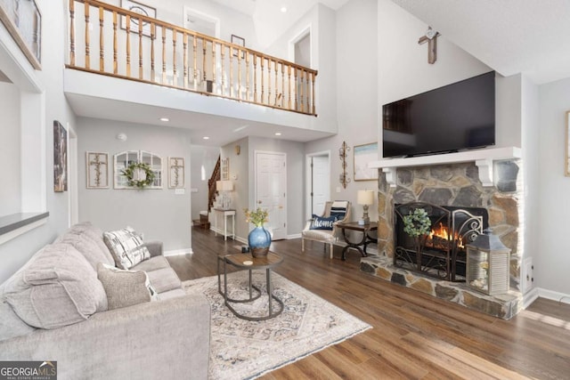 living room with hardwood / wood-style flooring, a towering ceiling, and a fireplace