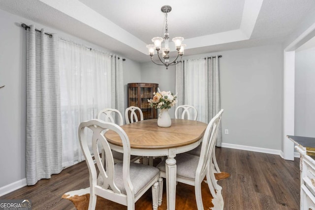 dining space featuring a notable chandelier, dark hardwood / wood-style flooring, and a tray ceiling