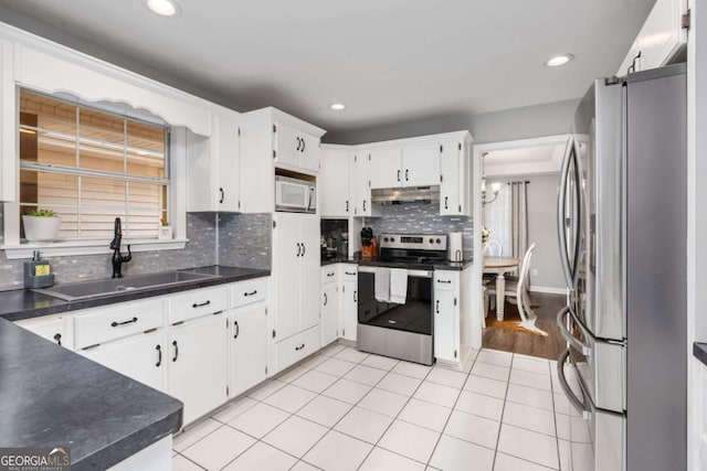 kitchen with appliances with stainless steel finishes, tasteful backsplash, sink, light tile patterned floors, and white cabinetry