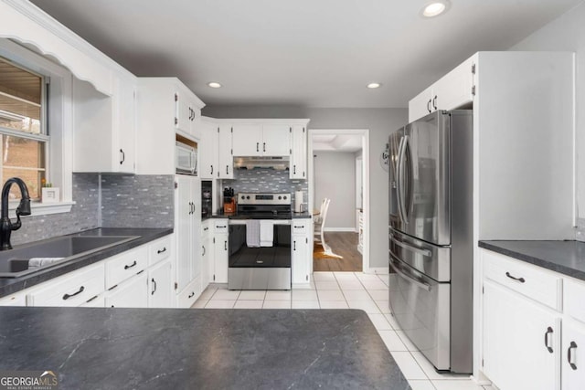 kitchen with appliances with stainless steel finishes, light tile patterned floors, white cabinetry, and sink