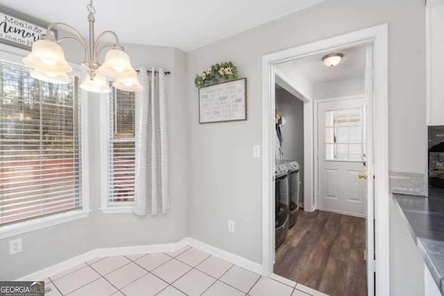 unfurnished dining area with tile patterned floors, separate washer and dryer, and a chandelier