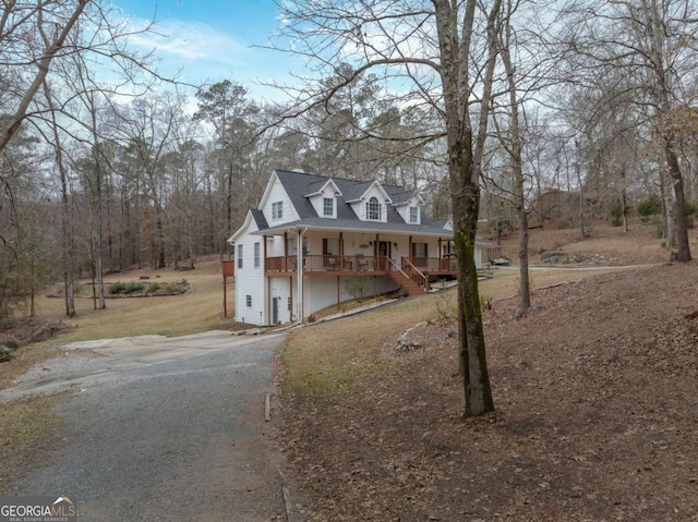 view of front of property featuring a garage, covered porch, and a front yard