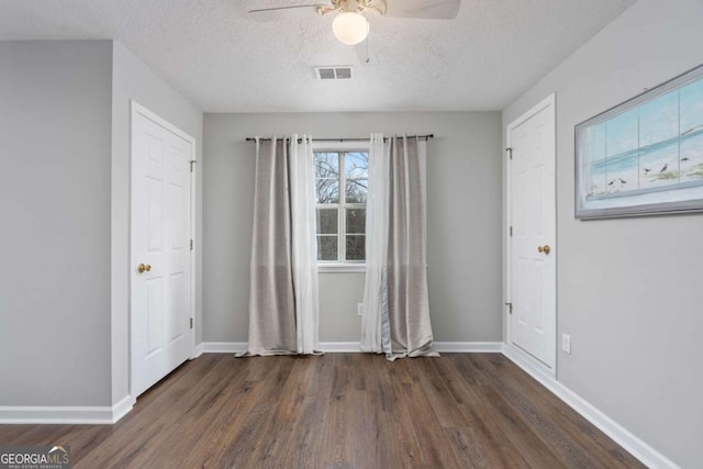 unfurnished room featuring a textured ceiling, dark hardwood / wood-style floors, and ceiling fan