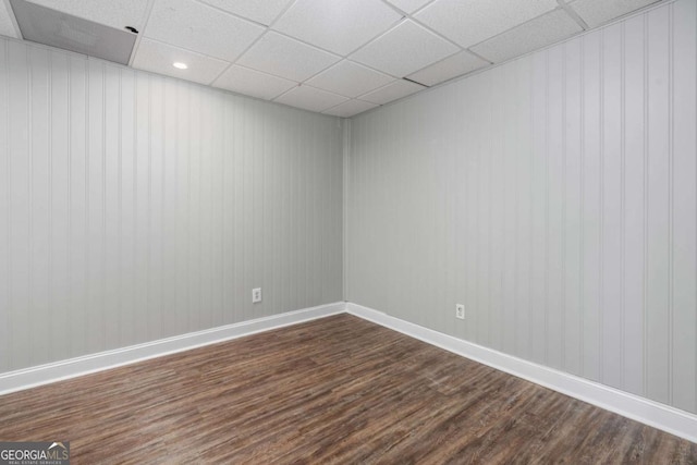 spare room featuring dark hardwood / wood-style flooring and a paneled ceiling