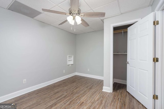 unfurnished bedroom with a closet, a drop ceiling, hardwood / wood-style flooring, and ceiling fan