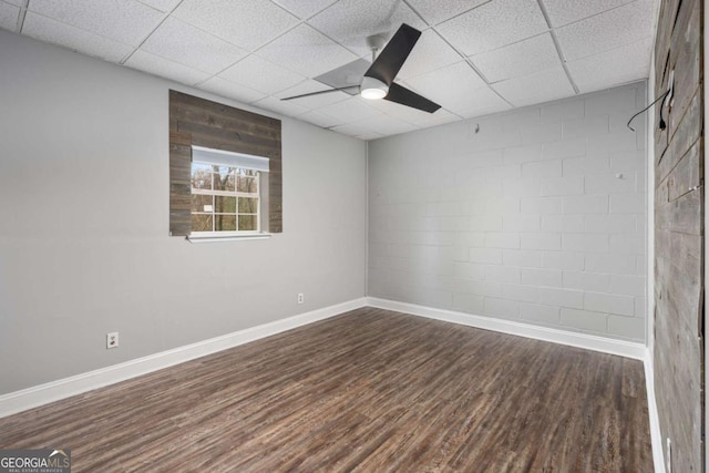 empty room featuring a paneled ceiling, dark hardwood / wood-style floors, and ceiling fan