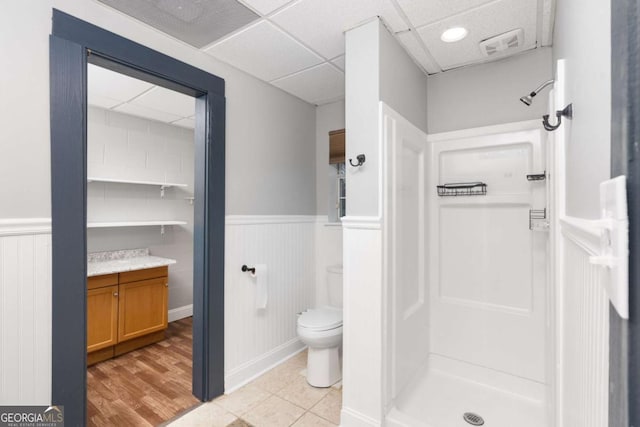 bathroom with a shower, tile patterned flooring, toilet, and a paneled ceiling