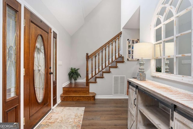 entryway with a wealth of natural light, dark hardwood / wood-style flooring, and vaulted ceiling