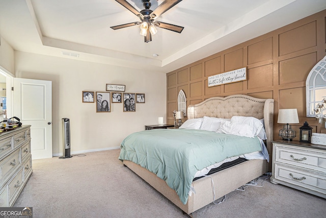 bedroom featuring a tray ceiling, ceiling fan, and light carpet