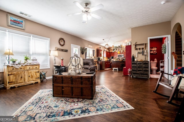 living room featuring ceiling fan with notable chandelier and dark hardwood / wood-style floors