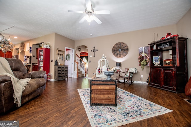 living room featuring ceiling fan, dark wood-type flooring, and a textured ceiling