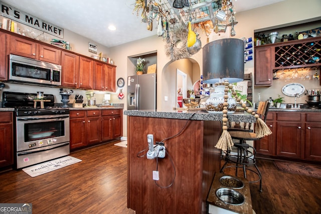 kitchen with dark hardwood / wood-style floors, a kitchen breakfast bar, and appliances with stainless steel finishes