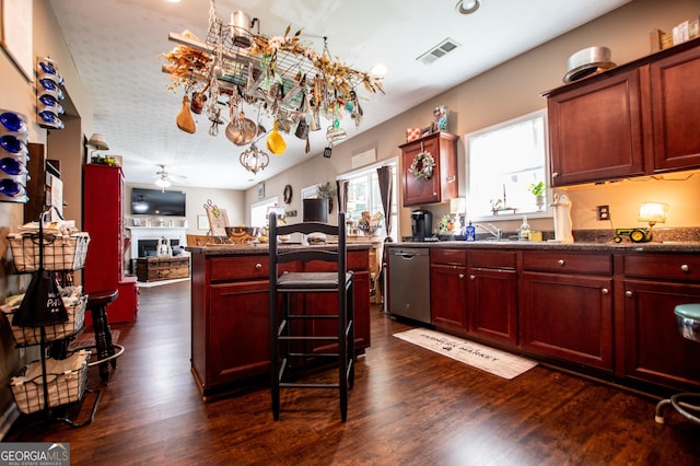 kitchen with a breakfast bar area, ceiling fan, dark hardwood / wood-style flooring, and stainless steel dishwasher