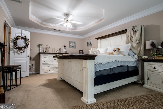 carpeted bedroom with a tray ceiling, ceiling fan, and crown molding