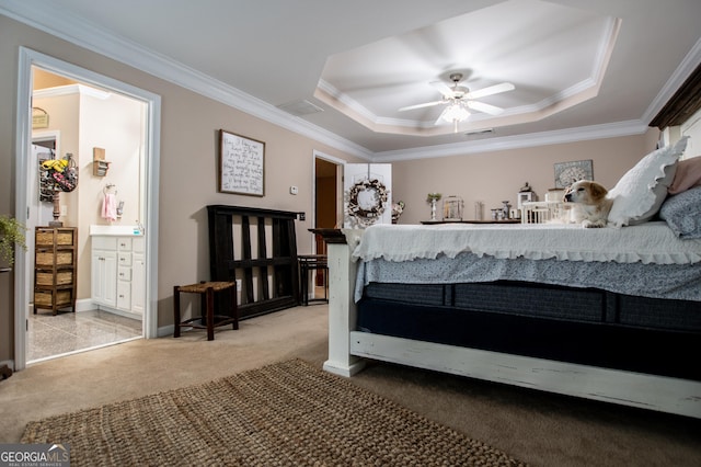 carpeted bedroom with ensuite bath, a raised ceiling, ceiling fan, and ornamental molding