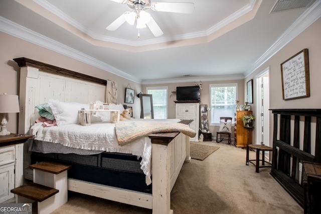 carpeted bedroom with ceiling fan, crown molding, and a tray ceiling