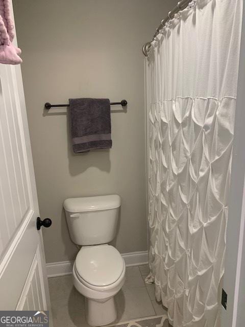 bathroom with a shower with curtain, tile patterned flooring, and toilet