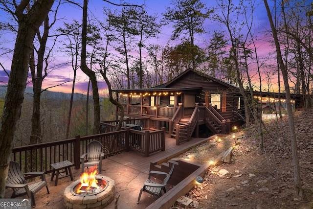 back house at dusk with a fire pit and a deck