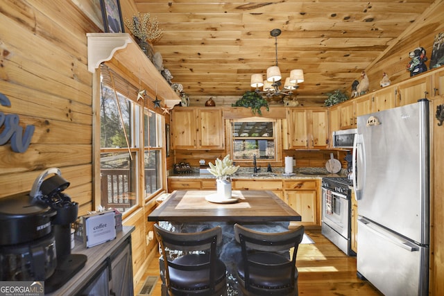 kitchen featuring appliances with stainless steel finishes, vaulted ceiling, pendant lighting, a chandelier, and butcher block counters