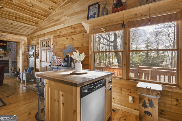 kitchen featuring lofted ceiling, a stone fireplace, stainless steel dishwasher, light wood-type flooring, and light brown cabinetry