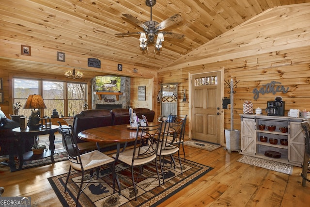 dining room featuring lofted ceiling, a stone fireplace, light hardwood / wood-style flooring, ceiling fan, and wood ceiling