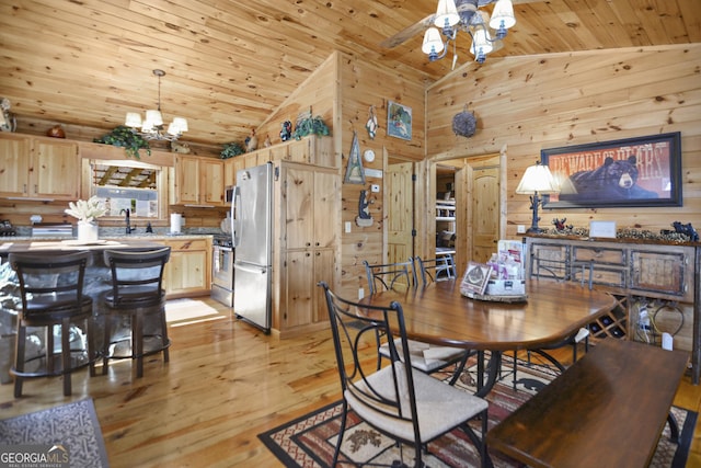 dining space featuring wood walls, light hardwood / wood-style flooring, wood ceiling, and ceiling fan with notable chandelier