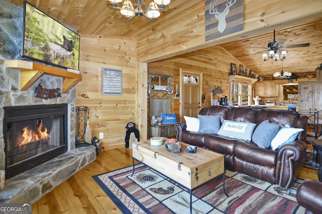 living room with wooden walls, ceiling fan with notable chandelier, wood ceiling, and lofted ceiling