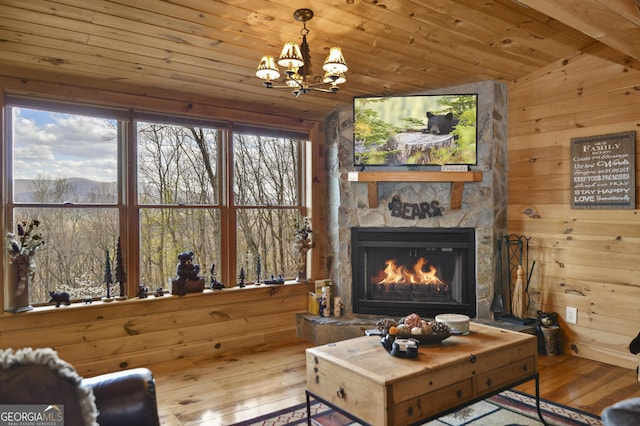 sitting room featuring wooden ceiling, a stone fireplace, vaulted ceiling, hardwood / wood-style flooring, and a notable chandelier