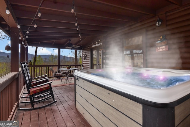 wooden terrace featuring a mountain view, ceiling fan, and a hot tub